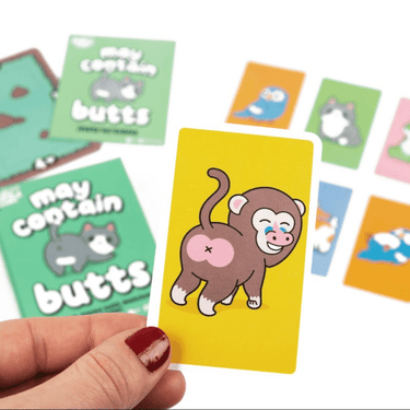 Professor Puzzle May Contain Butts party game with colorful cards and humorous illustrations for fun social gatherings.