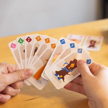 Helvetiq Odin family game box with colorful illustrations and game components on a wooden table.