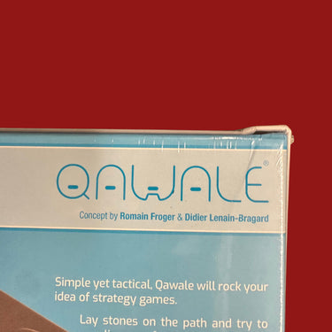 Qawale (DAMAGED) - scuffed top left corner of the box with wear along the left edge